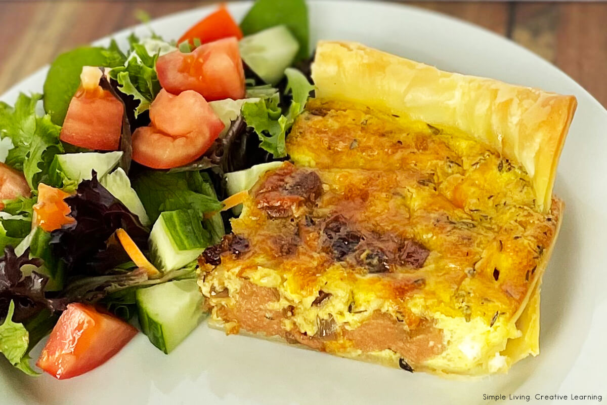 Caramelised Onion and Sausage Quiche on a plate with salad