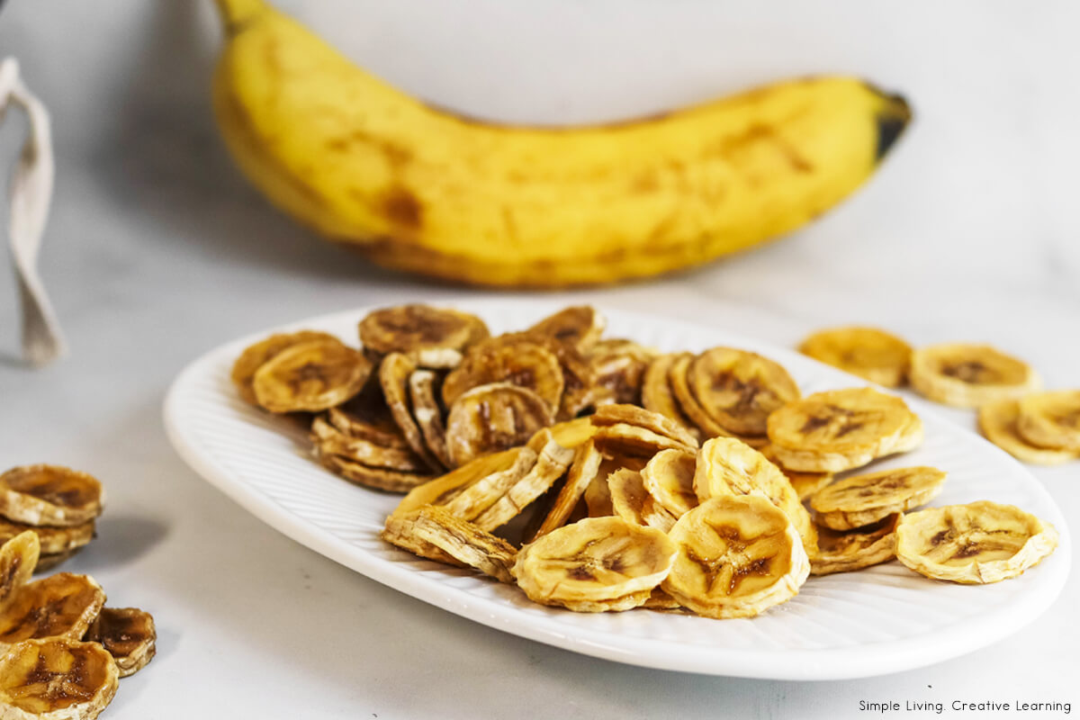 How to Dehydrate Bananas - dehydrated bananas on a plate with banana in background