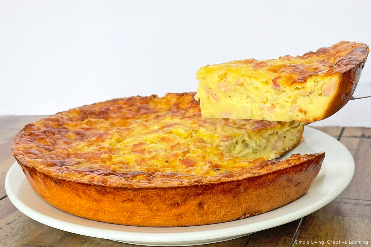 Easy Crustless Quiche Recipe on a plate with one piece cut out and held up above the quiche