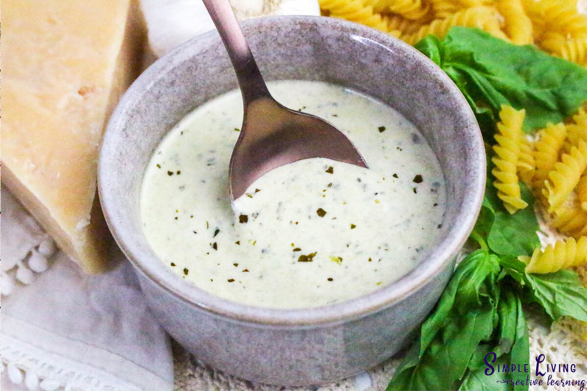 Homemade Alfredo Pesto Sauce putting a spoon in the sauce