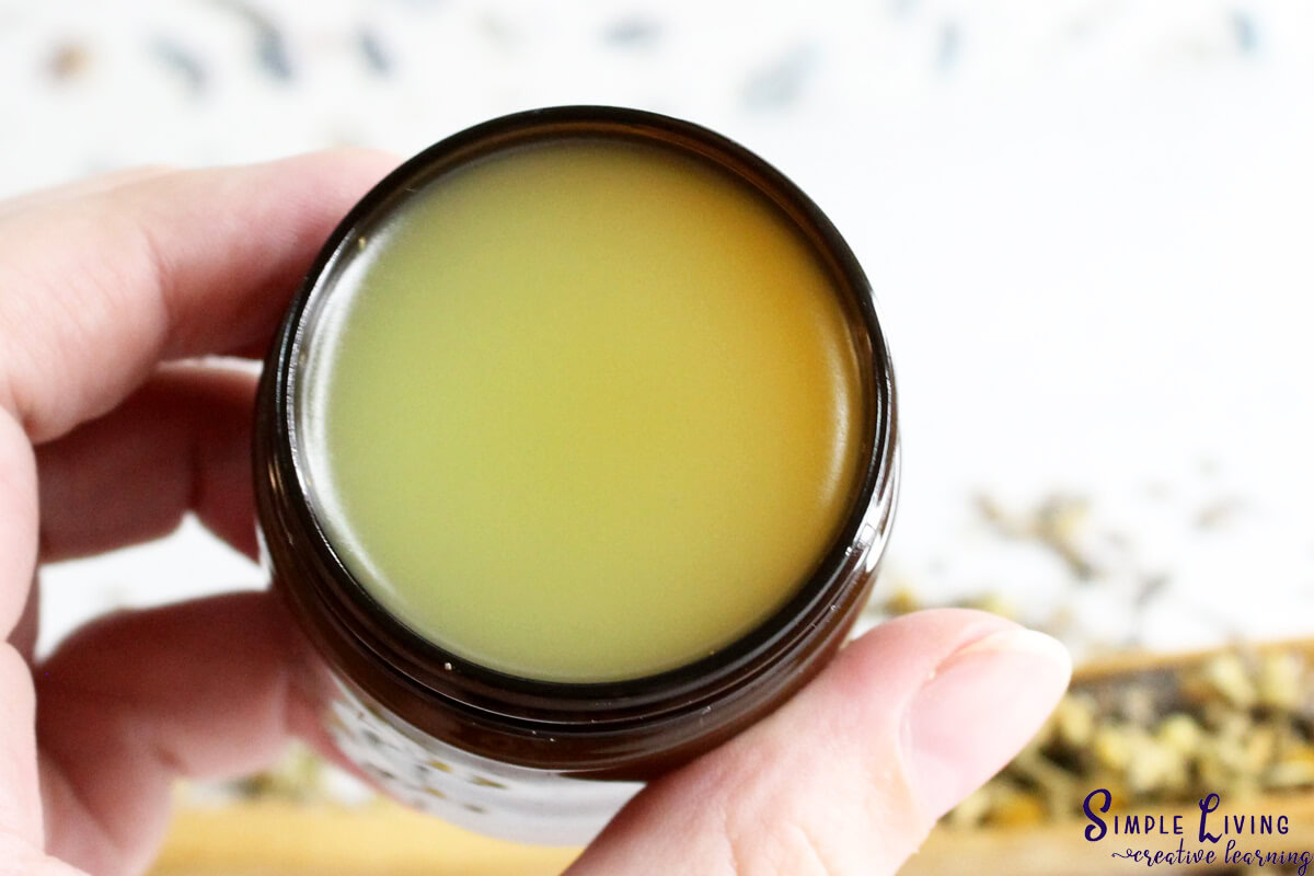 Homemade Natural Sleep Salve handing holding onto glass jar that contains the salve