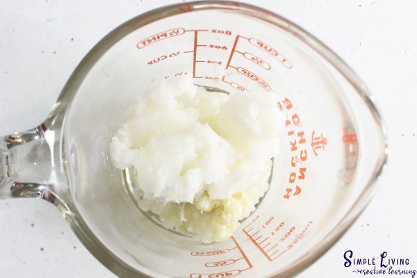 Homemade Dog Paw Balm adding ingredients to a glass jug