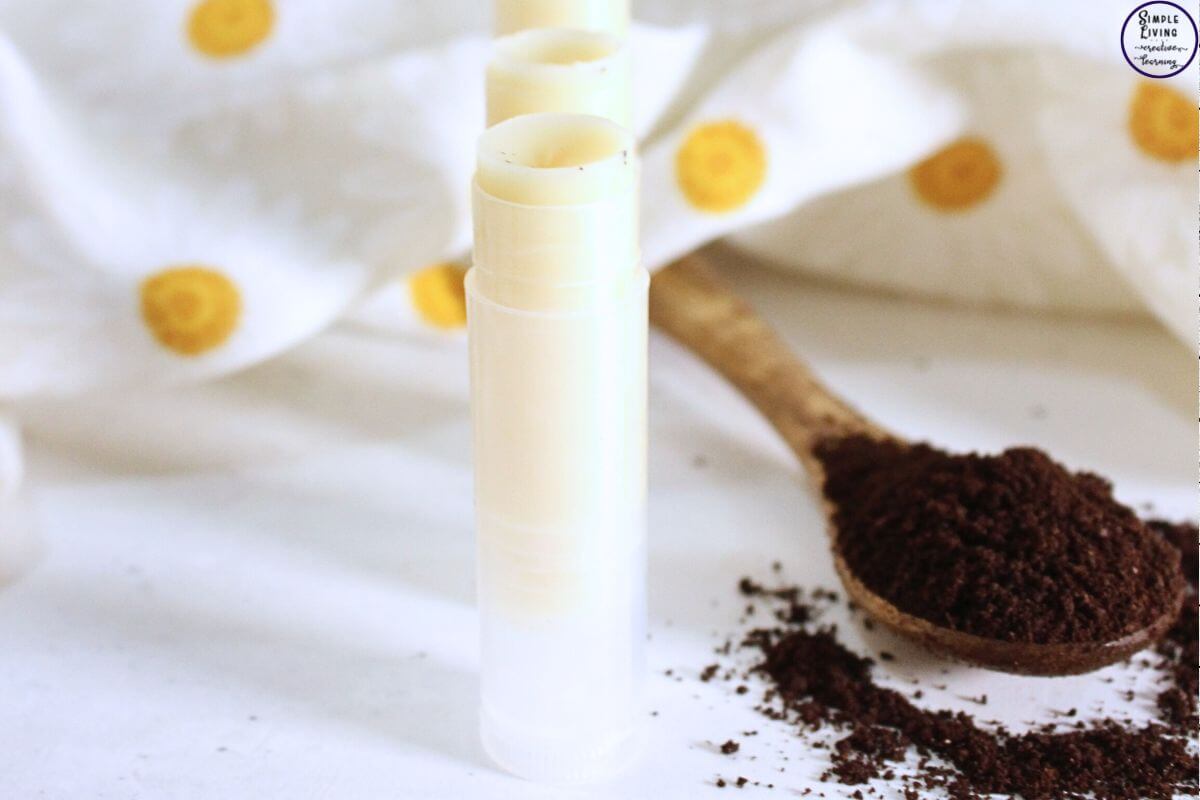Homemade Coffee Lip Balm in a tub next to a spoon of coffee