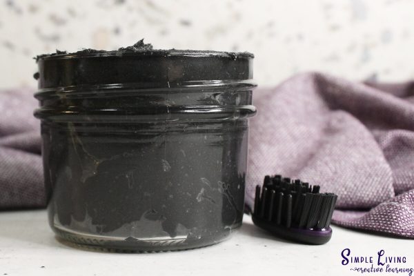 Homemade Natural Toothpaste in a glass jar with a toothbrush next to it