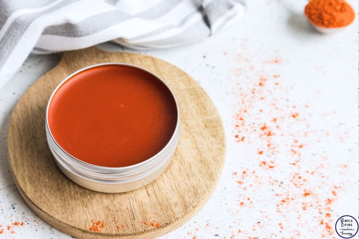 homemade cayenne salve in a tin sitting on a wooden board