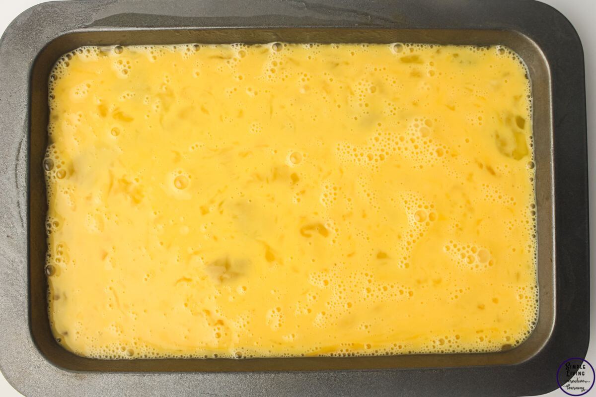 Freezer Friendly Sausage and Egg Muffins pouring into greased tray